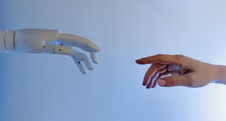 Human and AI hand connecting to illustrate collaboration in reinforced learning